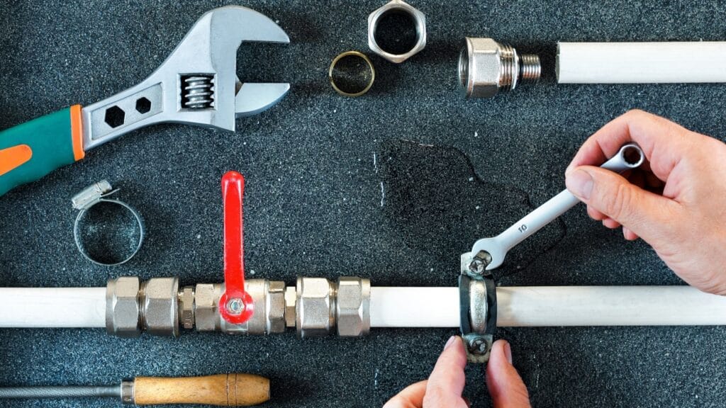 Plumber repairing a pipe valve with an adjustable wrench in Tucker