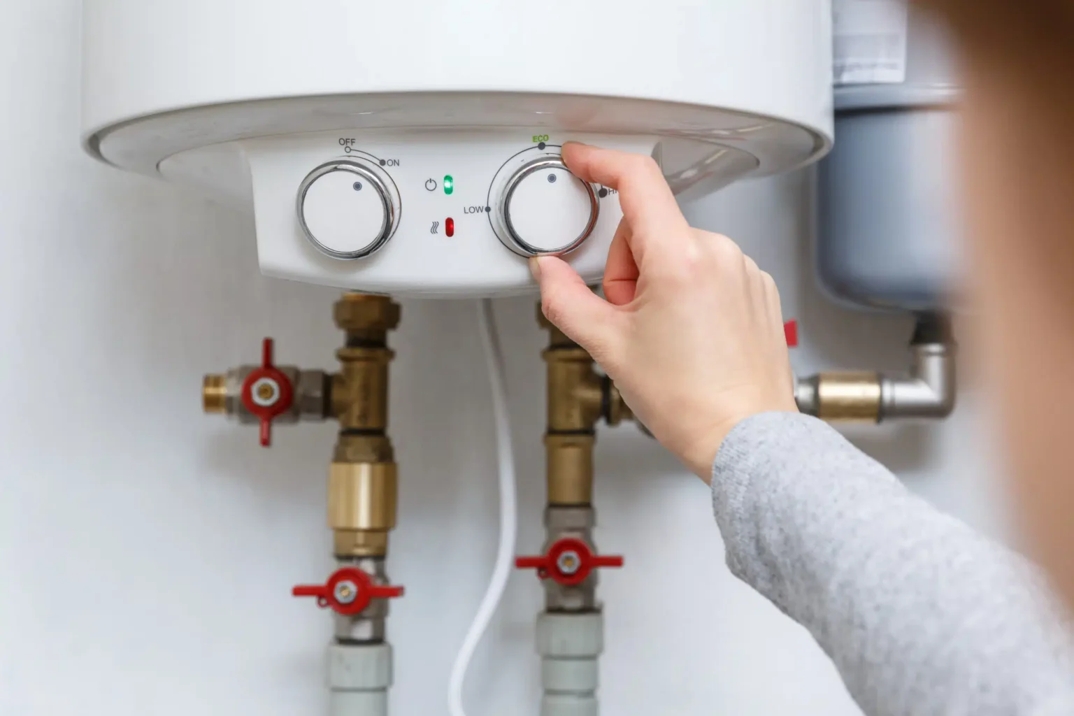 Homeowner adjusting the temperature controls on a water heater in Tucker